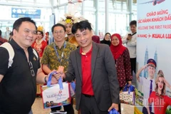 Ông Trần Hoàng Linh (phải), Giám đốc Văn phòng miền trung Vietjet đại diện hãng chào đón và tặng quà hành khách trên chuyến bay khai trương.