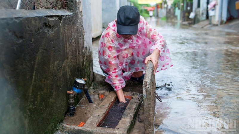 Nhiều người dân tranh thủ dọn dẹp nhà, khơi thông cống thoát nước khi nước rút bớt trong sáng nay. ndo_br_373a5ab7-ec6f-4b08-8a05-b4e39a6f438b-7529.jpg