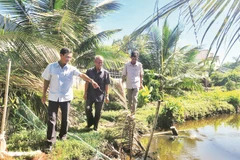 Ông Năm Dậu (giữa) cùng cán bộ địa phương đến tận nơi tìm hiểu, giải quyết ổn thỏa mâu thuẫn trong tranh chấp đất của hai hộ dân.