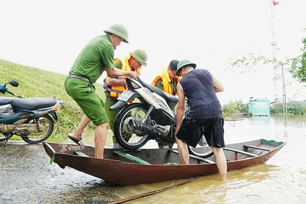 Công an xã Lam Thành (Nghệ An) hỗ trợ người dân vận chuyển xe máy lên đê tránh lũ.