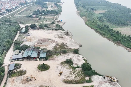 Cụm bến bãi tập kết cát nằm sâu trong một nhánh sông Hồng thuộc Công ty Cổ phần Thương binh Thành Luân, tách biệt khu dân cư, các mố cầu cảng được đắp dựng vươn ra sông để phục vụ việc vận chuyển cát từ dưới sông lên bãi. Ảnh chụp ngày 28/12/2025.