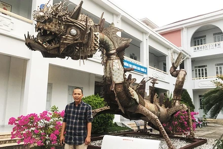 Họa sĩ Đinh Thanh Hải bên tác phẩm “Con rồng sắt” của nhà điêu khắc Pháp Marc Morvan, làm bằng phế liệu vỏ bom đạn, inox sau chiến tranh, hiện đặt tại sân Trường đại học Khánh Hòa.