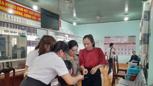 Đồng chí Ngô Thị Minh Trinh (bên phải)- Bí thư Đảng ủy xã Ea Knuếc, tỉnh Đắk Lắk, cùng cán bộ xã đang chỉ dẫn cho người dân làm thủ tục trên cổng dịch vụ công điện tử. (Ảnh LINH CẦM) 