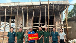 Cựu chiến binh Phạm Văn Lượng (đứng giữa) nhận hỗ trợ xây nhà mới. (Ảnh NGỌC LAN)