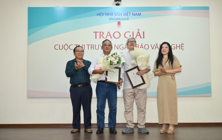 Hai tác giả đạt giải Ba, Phạm Xuân Hùng và Hà Đình Cẩn (thứ hai và ba từ trái sang) nhận Chứng nhận và hoa chúc mừng từ nhà thơ Trần Đăng Khoa, Phó Chủ tịch Hội Nhà văn Việt Nam và bà Trần Thị Phương Lan, Vụ trưởng Văn hoá Văn nghệ, Ban Tuyên giáo và Dân vận Trung ương. a3.jpg