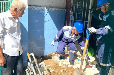 Một hộ dân ở đường Lê Văn Sỹ, phường Phú Nhuận cùng nhân viên Công ty cổ phần Cấp nước Gia Định trám lấp giếng khoan. (Ảnh: QUÝ HIỀN)