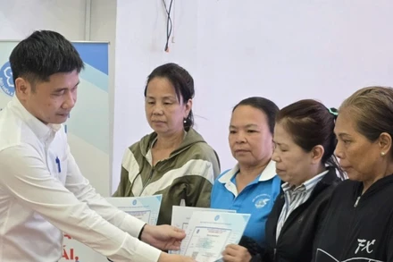 Ông Trần Dũng Hà, Phó Giám đốc Bảo hiểm xã hội Thành phố Hồ Chí Minh trao thẻ Bảo hiểm y tế cho phụ nữ có hoàn cảnh khó khăn. (Ảnh: QUÝ HIỀN)