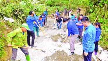Cán bộ, hội viên các tổ chức giúp nhân dân thôn Bản Lằn trộn bê-tông làm đường giao thông thôn, bản.