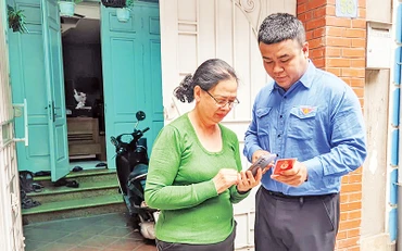 Đoàn viên thanh niên phường Thụy Khuê (Tây Hồ) hướng dẫn sử dụng ứng dụng “Sổ tay đảng viên điện tử Thành ủy Hà Nội”. (Ảnh VIẾT TUẤN)