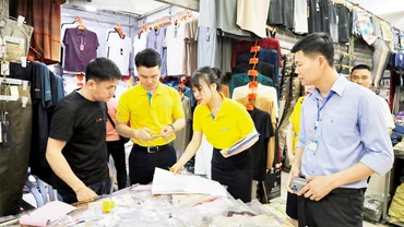 Nhân viên ngân hàng hướng dẫn hộ kinh doanh tại chợ Móng Cái thanh toán không dùng tiền mặt.