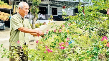 Thương binh Nguyễn Công Sáu chăm sóc vườn hoa của gia đình.