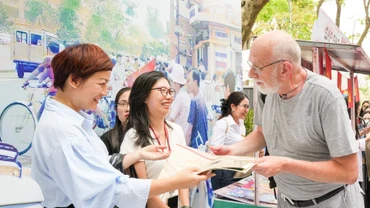 Du khách người nước ngoài trân trọng khi đón nhận tờ phụ san đặc biệt của Báo Nhân Dân.