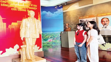 Bạn trẻ thưởng lãm tác phẩm “Bác Hồ về thăm quê hương Nghệ An lần thứ hai” của tác giả Nguyễn Xuân Tiên. (Ảnh MẠNH HẢO).
