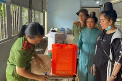 Hội viên phụ nữ Công an tỉnh Điện Biên hướng dẫn người dân cách khử khuẩn bằng chế phẩm sinh học. 