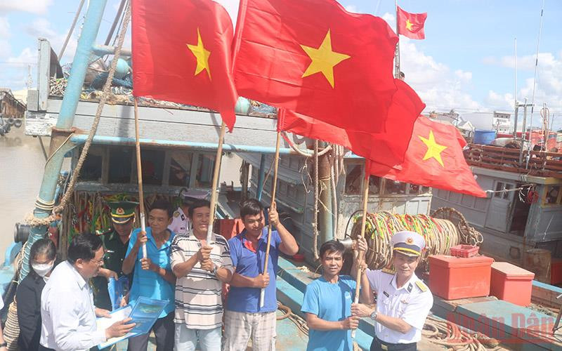 Cán bộ, chiến sĩ Vùng 2 Hải quân trao cờ Tổ quốc cho các chủ phương tiện tàu cá đánh bắt xa bờ tại Cảng cá Định An, thị trấn Định An, huyện Trà Cú.