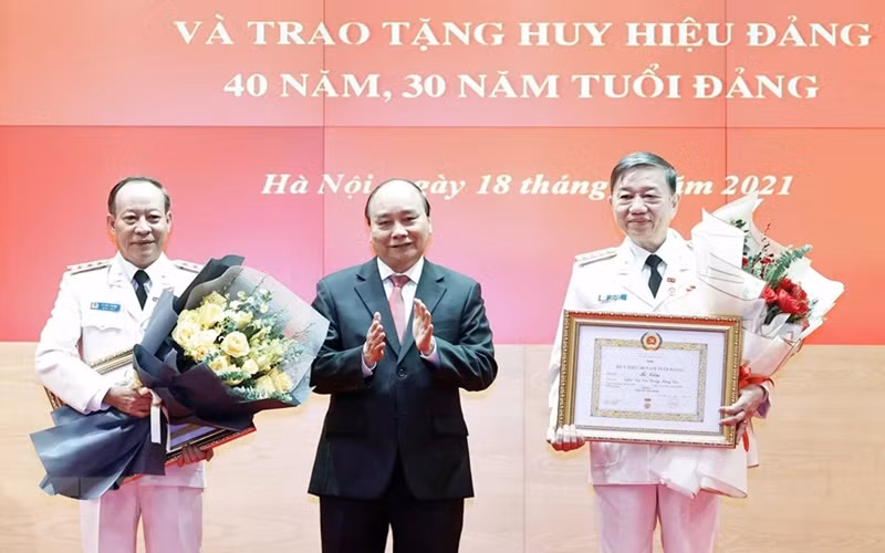 Chủ tịch nước Nguyễn Xuân Phúc trao tặng Huy hiệu 40 năm tuổi Đảng cho Đại tướng Tô Lâm, Ủy viên Bộ Chính trị, Bộ trưởng Công an, và Thượng tướng Lê Quý Vương, nguyên Ủy viên Trung ương Đảng, nguyên Thứ trưởng Công an. (Ảnh: TTXVN)