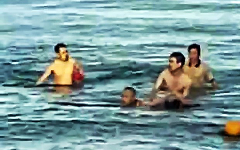 Hình ảnh Trung tá Bùi Văn Nhiên cùng người dân cứu cháu bé bị đuối nước. (Ảnh: qdnd.vn)