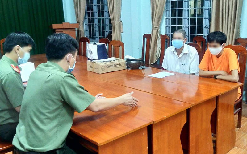 P.T (áo cam) làm việc với cơ quan chức năng.