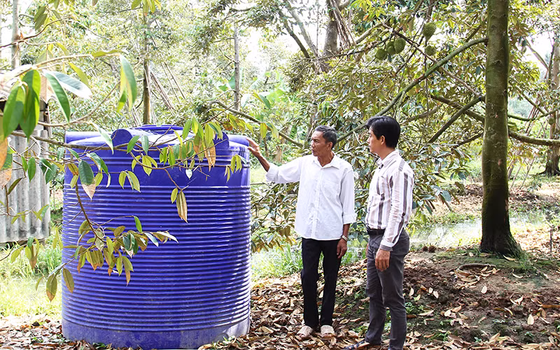 Nông dân Phẩm Văn Tiếu (xã Thanh Bình, huyện Vũng Liêm, Vĩnh Long) bên thùng chứa nước ngọt phòng hạn, mặn cho vườn sầu riêng của gia đình. Ảnh: BÁ DŨNG