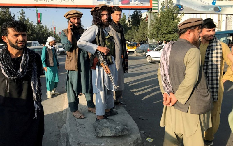 Một tay súng Taliban (giữa) đứng bên ngoài sân bay quốc tế Hamid Karzai, tại Kabul, ngày 16/8. (Ảnh: Reuters)