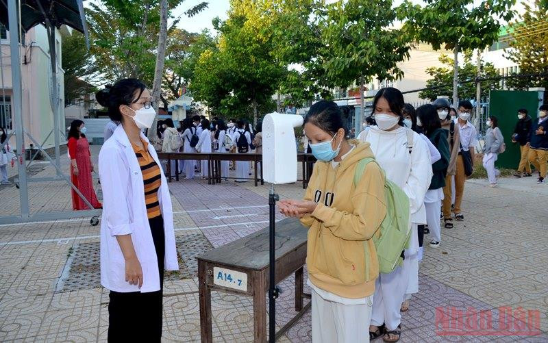 Học sinh thực hiện kiểm tra thân nhiệt và rửa tay sát khuẩn trước khi vào lớp học tại Trường trung học phổ thông Phan Bội Châu, thành phố Phan Thiết (Bình Thuận).
