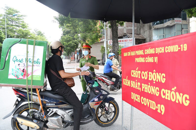 Lực lượng chức năng phường Cống Vị, quận Ba Đình kiểm tra giấy tờ tùy thân tại chốt kiểm soát dịch Covid-19 trên phố Đội Cấn. (Ảnh: THANH HẢI)