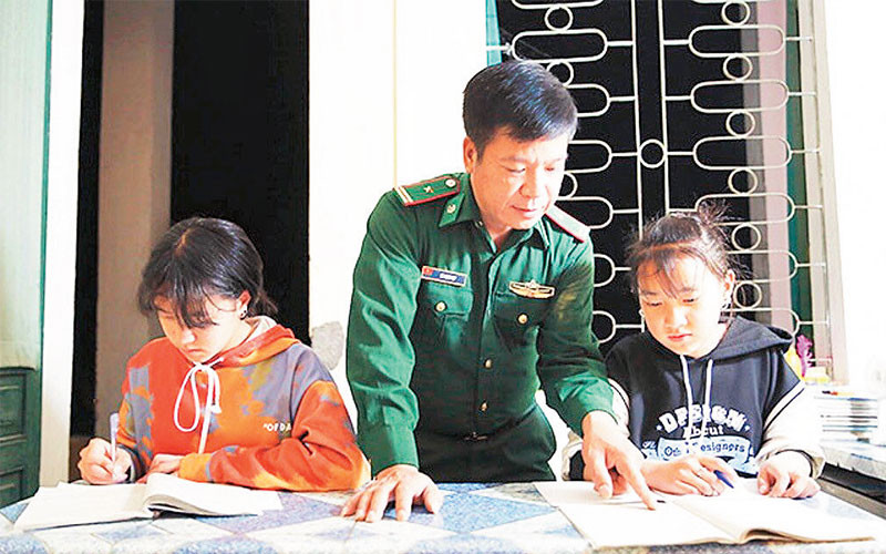 Thiếu tá Lê Mạnh Hợp, Chính trị viên phó Ðồn Biên phòng Phó Bảng (Hà Giang) hướng dẫn các con nuôi học bài. 