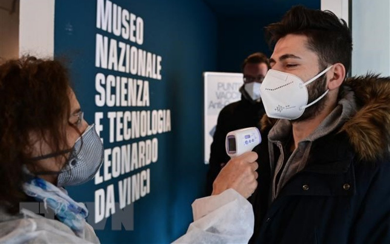 Nhân viên y tế kiểm tra thân nhiệt phòng lây nhiễm Covid-19 tại Milan, Italy. (Ảnh: AFP/TTXVN)