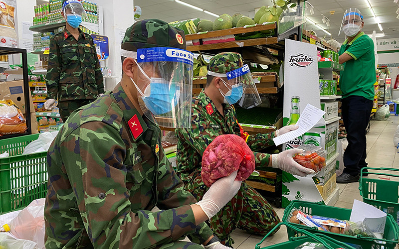 Các chiến sĩ chọn hàng theo đơn tại cửa hàng theo yêu cầu mua hộ của người dân phường 2, quận 5, TP Hồ Chí Minh. (Ảnh: Quý Hiền)
