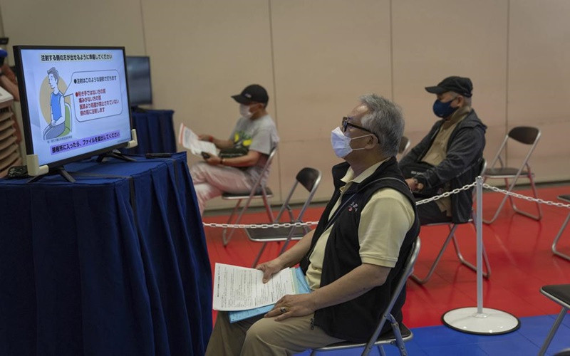 Người dân theo dõi hướng dẫn tiêm vaccine ngừa Covid-19 tại trung tâm tiêm chủng ở Tokyo. (Ảnh: AP)