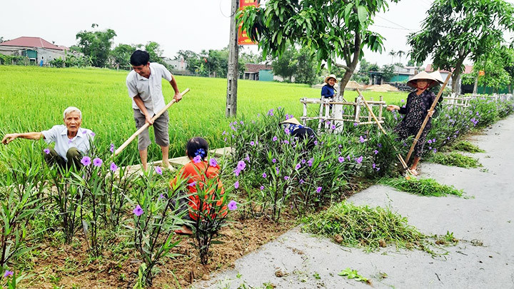 Người dân cắt tỉa cây hàng rào xanh bên đường liên thôn.
