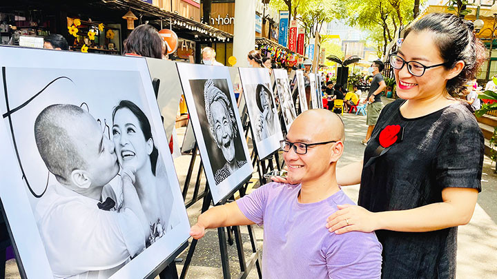 Vợ chồng vận động viên khuyết tật Nguyễn Hồng Lợi bên bức ảnh tại triển lãm.