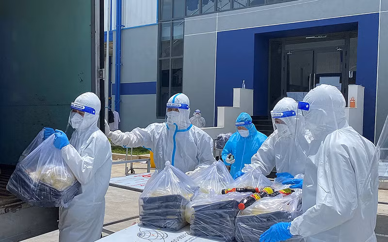 Các F0 khỏi bệnh hỗ trợ đưa cơm cho bệnh nhân tại Khu điều trị bệnh nhân Covid-19 Thới Hòa (Bình Dương).