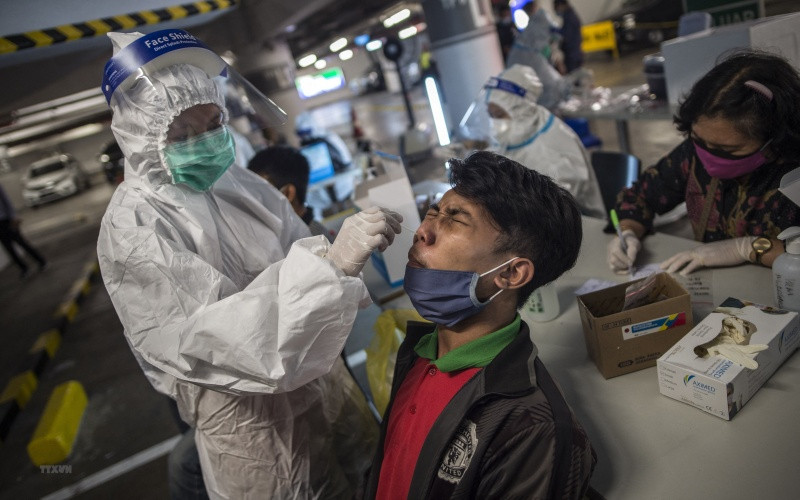 Nhân viên y tế lấy mẫu xét nghiệm Covid-19 cho người dân tại Surabaya, Indonesia ngày 17/6/2021. (Ảnh: AFP/TTXVN).