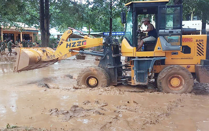 Phụ huynh đưa xe ủi đến giúp Trường tiểu học - THCS Cam Tuyền, huyện Cam Lộ (Quảng Trị) dọn bùn sau lũ. Ảnh: LÂM QUANG HUY