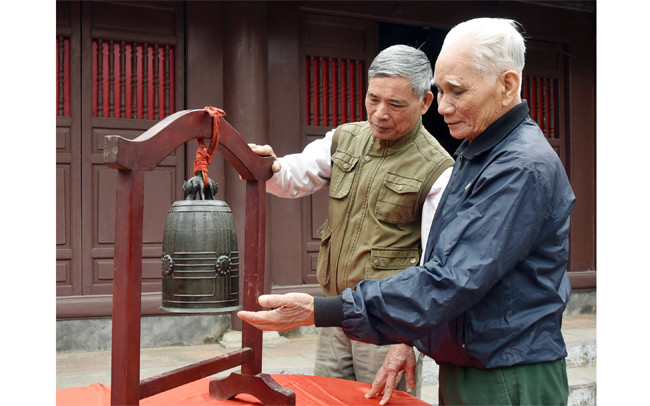 Người dân Đông Ngạc (Hà Nội) bên bảo vật quốc gia Chuông đình Nhật Tảo. Ảnh: TRẦN HẢI