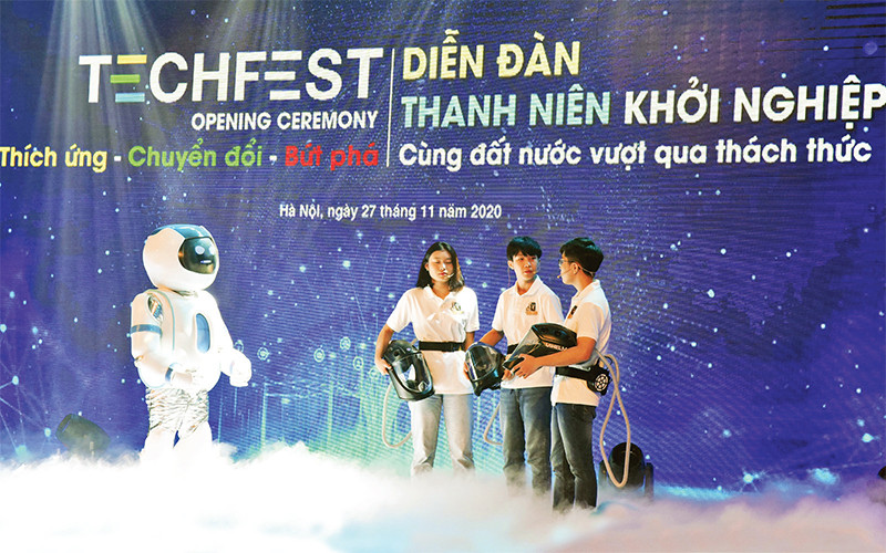 Màn đối thoại giữa rô-bốt và nhóm tác giả mũ cách ly di động Vihelm chống dịch Covid-19 tại lễ khai mạc diễn đàn Thanh niên khởi nghiệp năm 2020. Ảnh: ÐỨC ANH