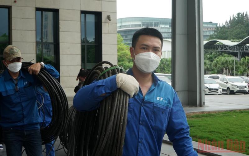 Anh Nguyễn Huy Ánh (bên phải) và đồng nghiệp thực hiện đấu nối đường tnternet đi quốc tế tại Trung tâm Hội nghị quốc gia.