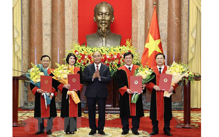 Chủ tịch nước Nguyễn Xuân Phúc trao quyết định và tặng hoa chúc mừng 4 thẩm phán Tòa án Nhân dân tối cao. (Ảnh: TTXVN) 
