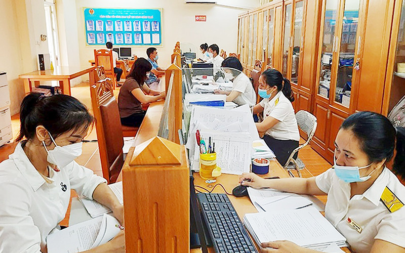 Cán bộ Chi cục Thuế khu vực Vĩnh Tường (Vĩnh Phúc) hướng dẫn người dân nộp thuế. Ảnh: HỒNG TÍNH