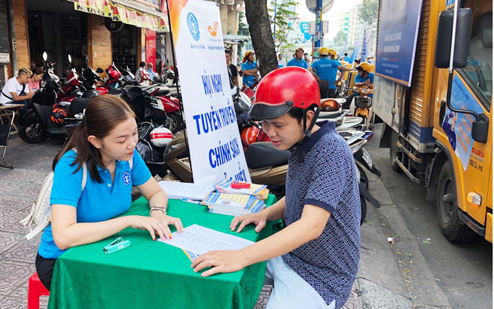 Cán bộ bảo hiểm xã hội TP Hồ Chí Minh tuyên truyền chính sách BHYT, BHXH cho người dân. Ảnh: MINH ANH