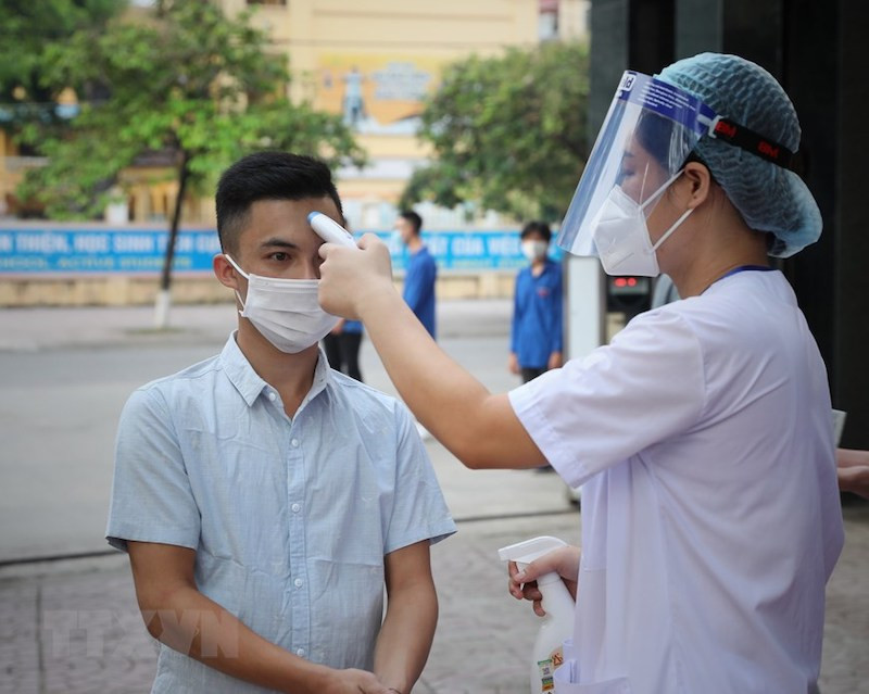 Kiểm tra thân nhiệt cho thí sinh trước khi vào điểm thi tại Hội đồng thi Bắc Giang. Ảnh: DANH LAM/TTXVN