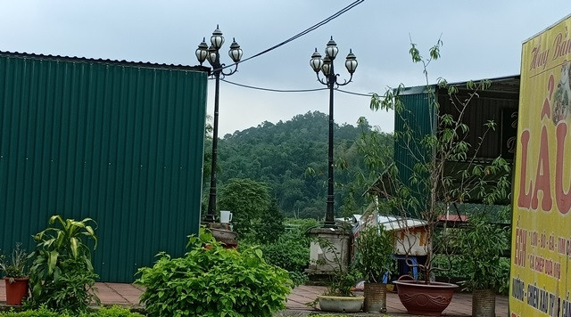 Hai cột đèn nằm “ép” giữa các hàng quán dựng trên đỉnh kè sông Cầu.