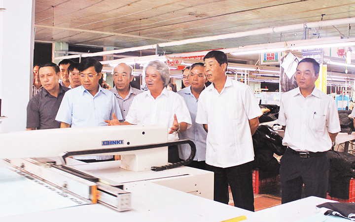 Anh hùng Lao động Nguyễn Hữu Phải (người thứ tư từ phải sang) giới thiệu hệ thống máy lập trình tự động trong ngành may. Ảnh: ĐỨC THANH 