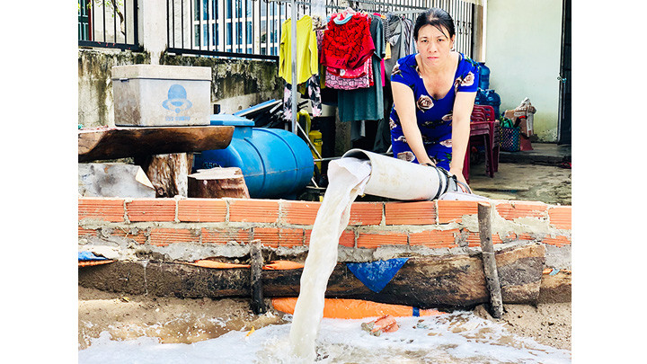 Chị Giang Thị Phúc bơm nước xả ra đường.