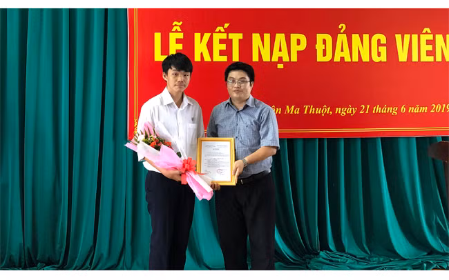 Đồng chí Phạm Công Tuấn (bên phải), Bí thư Chi bộ 2 Trường THPT chuyên Nguyễn Du trao quyết định cho đảng viên mới được kết nạp.