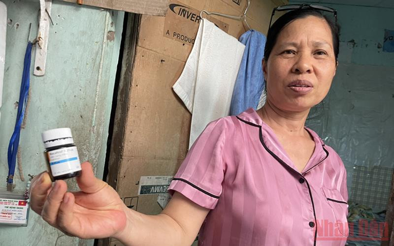 Bà Mai Thị Hường cùng lọ thuốc canxi dạng viên dùng tạm thay thế trong khi hết thuốc. (Ảnh: SƠN BÁCH)