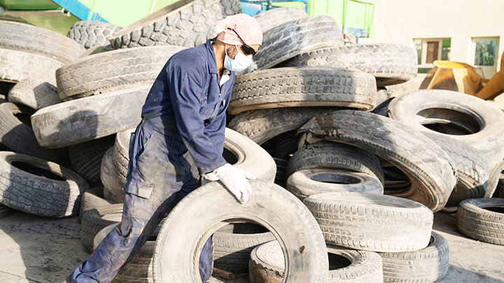 Một công nhân chuẩn bị đưa lốp xe cũ vào tái chế. Ảnh: REUTERS