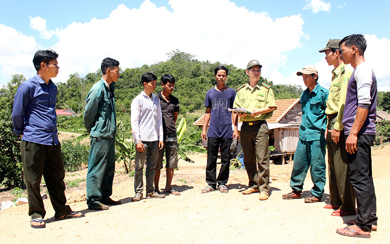 Người dân nhận khoán bảo vệ rừng trao đổi với cán bộ kiểm lâm Ban quản lý rừng phòng hộ Mang Yang. 