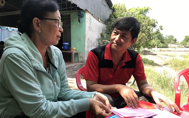 Bà Thị Nhàn, đại lý thu BHXH, BHYT trao đổi và chia sẻ kinh nghiệm vận động người dân tham gia chính sách BHXH với anh Võ Văn Dũng. Ảnh: THÁI BÌNH